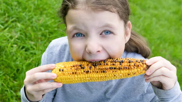 Niña Sostiene Sus Manos Una Mazorca Maíz Asado Muerde Los — Foto de Stock