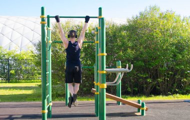 bir adam açık havada spor yaparken müzik dinler, doğanın bir arka plan karşı, yatay bir barda