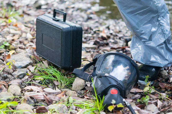 black mask for respiratory protection and vision, lies on the contaminated ground, next to the suitcase, there is a place for the inscription