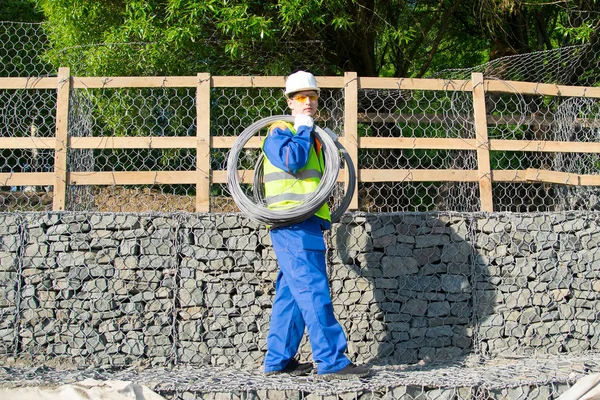 Worker White Helmet Background Wooden Fence Building Stones Carries Wire — Stock Photo, Image