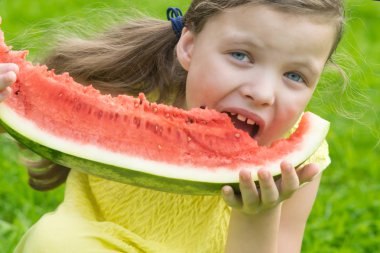 sarı elbiseli kız kırmızı karpuz bir dilim yiyor