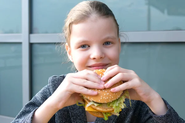 Mädchen Lächelt Hält Einen Leckeren Burger Der Hand Sitzt Tisch — Stockfoto