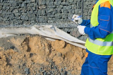 Levhanın yakın çekimleri, taşlarla sahili güçlendirmek için yapılan işlerin kaydını tutan müteahhidin ellerinde, yazıtların bir yeri var.