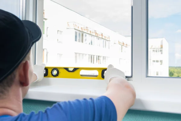 the window replacement wizard checks the window sill installation level with a yellow instrument