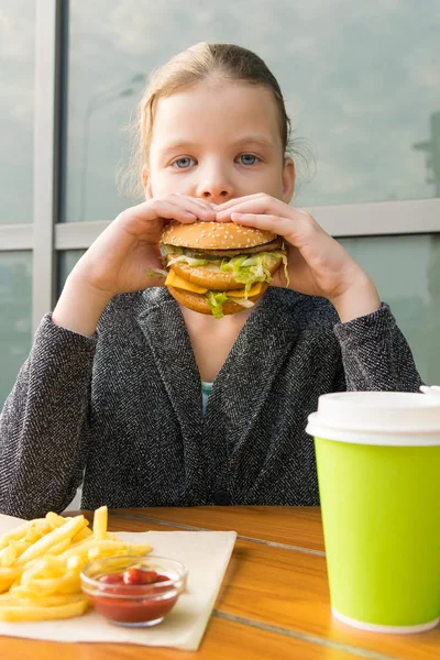 女子高生がレストランのテーブルでファーストフードを食べ — ストック写真