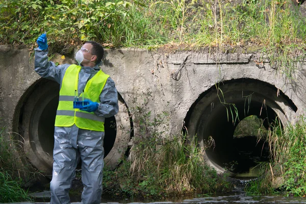 Wetenschapper Een Beschermend Pak Masker Achtergrond Van Rioolbuizen Met Reageerbuizen — Stockfoto