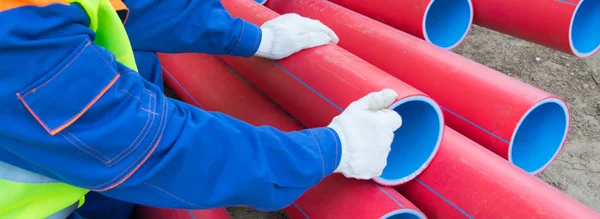 Arbetare Händer Vita Handskar Mot Bakgrund Röda Plaströr Staplade Ovanpå — Stockfoto