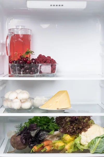 separate storage of products, berries, dairy products, vegetables on different shelves in an open refrigerator