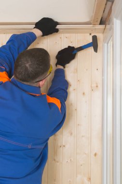 Mavi üniformalı usta tavana bir kovan çiviledi.