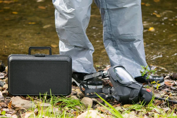 equipment and mask of a laboratory specialist for conducting a mobile environmental analysis lies on the ground, against the background of the river