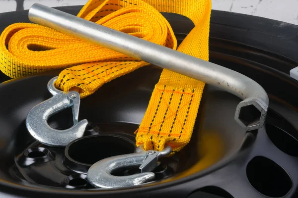 close-up of the tow rope and key for removing the wheel, against the background of the metal black disc of the car