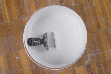 Beton duvarlar için beyaz macun ve uygulamak için spatula olan kovayı kapat.