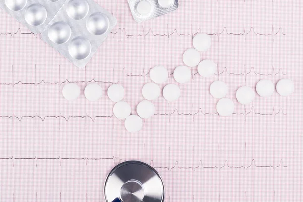 paper with the readings of the heartbeat with white pills, close-up background