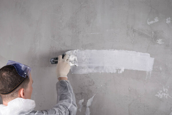 a man in special clothes conducts plastering work on the wall, back view