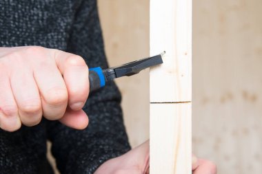 Yakın plan, penseyle el, ahşap bir çubuktan metal çivi çıkarmak.