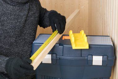 Siyah eldivenli bir adam alet çantasındaki tahta bir blok büyüklüğünde.