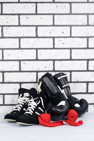 shoes and boxing gloves, red protective bandages for protecting hands on a white brick background