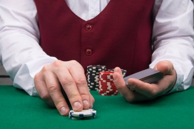Krupiye, poker oyununda bahsi arttırır masaya cips ekleyerek, yakın plan.