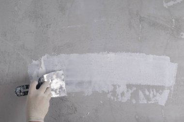 Bitiş macununu beton duvara sürerken, bir ustanın eliyle, yazıtlar için bir yer vardır.