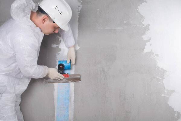 the master applies a reinforced tape with a spatula to strengthen the plastered crack, there is a place for the inscription