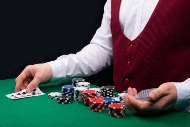 Krupiye yeşil bir masada, oyun kağıtları ve çipleri seriyor.