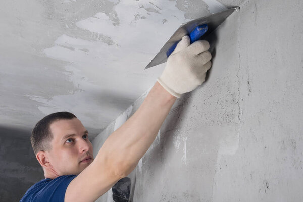 a man in blue special clothes repairs a concrete ceiling, bottom view
