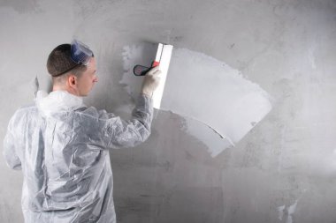Usta beton duvarı, büyük bir spatulayı yıkmak için çalışır, beyaz bir solüsyon uygular, yazılar için bir yer vardır, dikiz manzarası