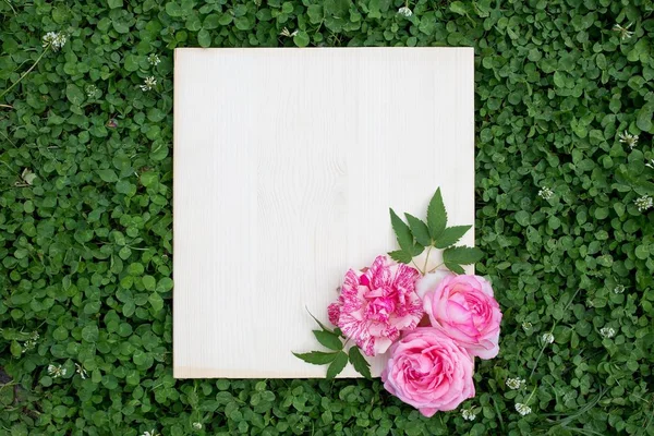 Renkli gül ve yeşil çimenlerin üzerinde ahşap tahta. Aşk kavramı.