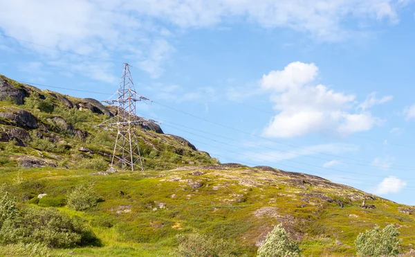 A lone electric iron pole on a mountain surrounded by greenery. Wired electricity is the most environmentally friendly type of energy. In the photo the hill lies diagonally with the sky