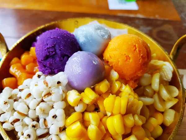 Sesame dumplings and sweet purple mashed potatoes in brass bowl; dessert