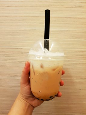 İnci kabarcıklar buzlu süt çay kahverengi zemin üzerine