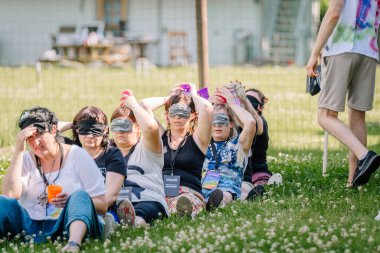 Sigulda, Letonya - 18 Temmuz 2025 - Bir hippi festivaline katılanlar çimlerin üzerinde otururken bir takım kurma oyununa katılıp açık havada eğlenceli ve güvenilir bir grup aktivitesi yaratıyorlar..