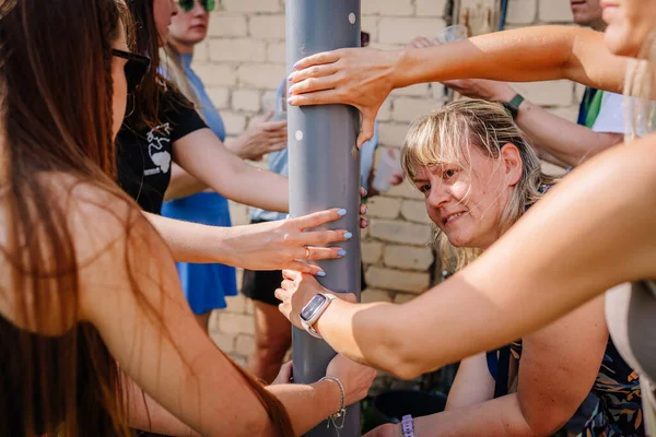 Sigulda, Letonya - 18 Temmuz 2025 - Hippi tarzı bir açık hava etkinliğinde bir grup kadın takım oluşturma ya da oyun etkinliğinin bir parçası olarak bir boruya dokunmak ve dengelemek için birlikte çalışıyorlar..