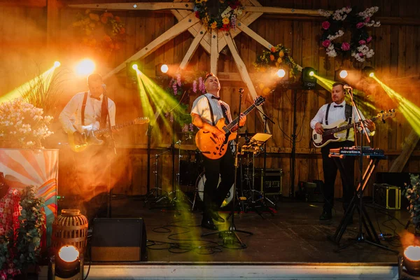 Sigulda, Letonya - 18 Temmuz 2025 - Canlı müzik grubu canlı bir hippi festivalinde dramatik ışıklar altında, gitaristlerin, basçıların ve klavyecilerin sahne aldığı sahnede sahne aldı..