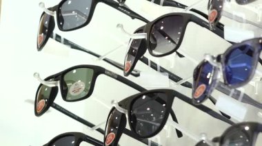 Valmiera, Letonya - 10 Eylül 2025 - Perakende satışta% 20 indirimli etiketli çeşitli güneş gözlükleri, polarize lensler ve çerçevelerde görünür marka isimleri.