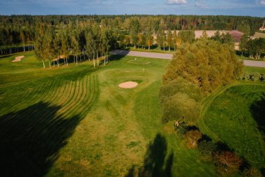 İyi korunan golf sahasının havadan görünüşü. Kum sığınakları, ağaçlar, gölgeler ve güneş ışığı altında bir kulüp alanı..