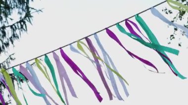 Açık hava hippi festivalinde rüzgarın esintisinde açık havada parlak bir gökyüzüne bağlı renkli kurdeleler. Basit, neşeli ve dekoratif bir sahne..