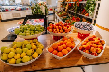 Elmalar, portakallar, erikler, şeftaliler ve şeftaliler de dahil olmak üzere çeşitli taze meyveler bir otel veya restoranda büfe tezgahında beyaz kaselerde sergilenmektedir..