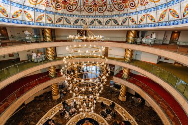 Kemer, Tureky - Eylül 18, 2025 - Çok katlı atriyum, dekoratif avize, vitray tavan, spiral sütunlar ve yukarıdan görülen zarif oturma alanı ile büyük otel iç mimarisi.