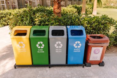 Color-coded recycling bins labeled for plastic, glass, metal, paper, and organic waste. Outdoor public sorting station in Turkey promoting eco-friendly habits.