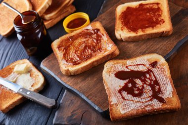 aussie savory toasts for breakfast with butter and vegemite- a thick Australian healthy food spread made from leftover brewers yeast extract with vegetables and spices, view from above, close-up clipart