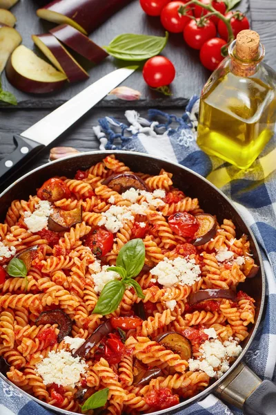 素食意大利面食 Fusilli 与茄子 西红柿 芝士在一个锅里的成分在背景 垂直视图从上面 — 图库照片