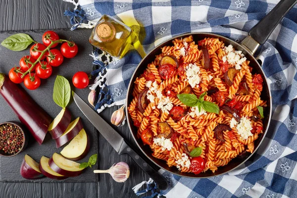 素食意大利面食 Fusilli 与茄子 西红柿 芝士在一个木制的餐桌上的配料在背景 从上面看 — 图库照片