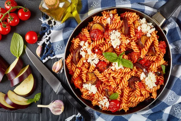 意大利面食 Fusilli 与茄子 西红柿 芝士在一个木制的餐桌上的配料在背景 垂直视图从上面 — 图库照片