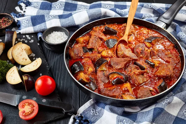 茄子ビーフ シチュー クローズ アップからキッチン タオルとペルシャの料理の成分表示と黒い木のテーブルのフライパン シチュー Bademjan — ストック写真