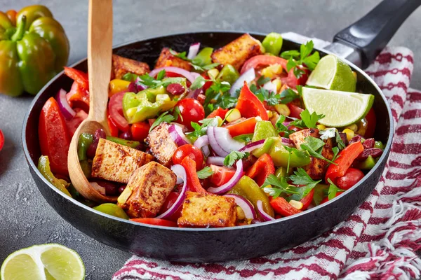 vibrant,veggie Mexican dish made from red bell pepper, green bell pepper, fresh tomatoes, onion, corn, black beans, parsley, tofu cheese with lime, olive oil and barbeque sauce dressing, close up