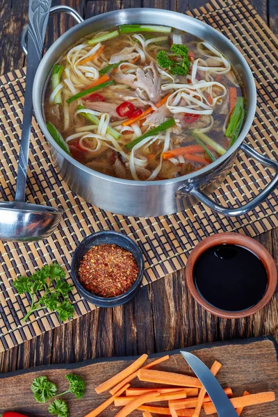 鴨鍋とボード アジア料理 上からビューの垂直方向の成分を持つ古い素朴なテーブルの上に金属鍋で野菜麺 — ストック写真