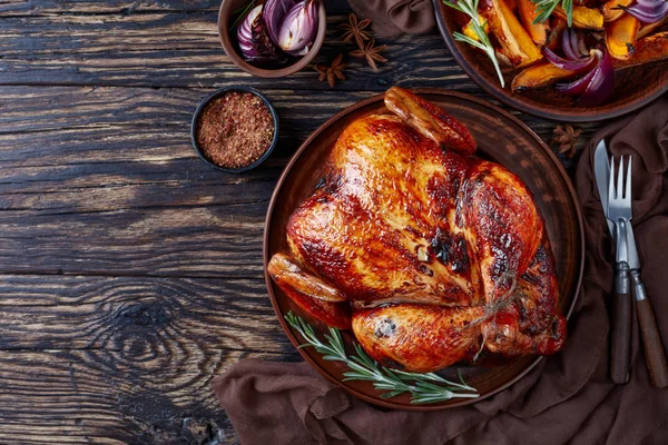 Whole roasted chicken with golden brown crispy skin served on a earthenware dish with caramelized grilled pumpkin slices and grilled onion, view from above, flat lay, copy space — Stock Image Whole Roasted Chicken Golden Brown Crispy Skin Served Earthenware Dish Stock Photo