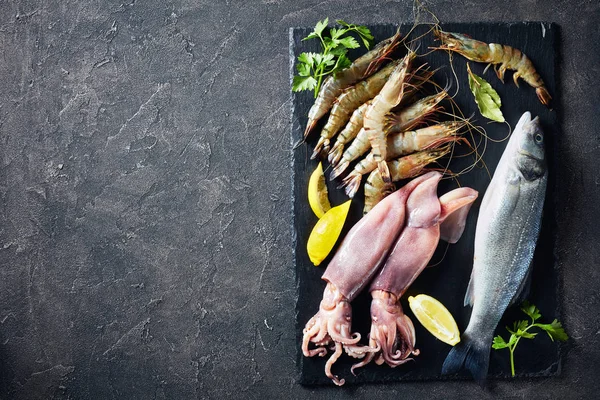 Sea bass, king prawns, calamari, lemon slices — Stock Photo, Image