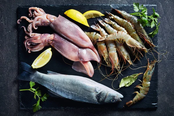 Sea bass, king prawns, calamari, lemon slices — Stock Photo, Image